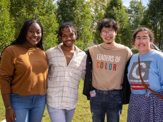 Four students smiling for a photo, one student wearing a "Leaders of Color" t-shirt.